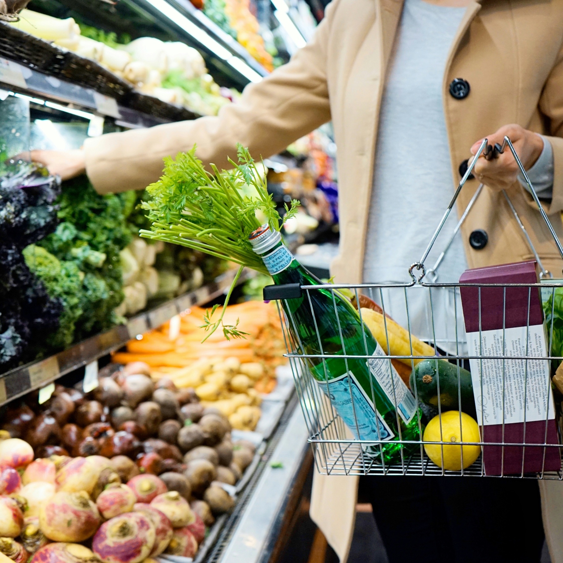 Shopper selecting fresh produce with a grocery basket
